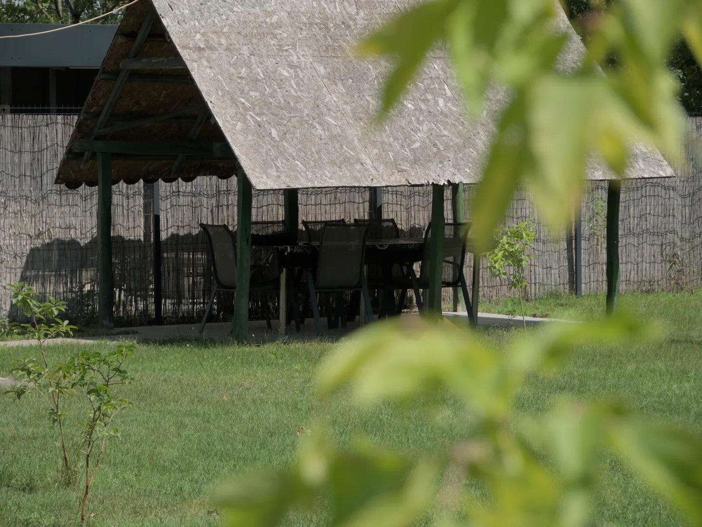 A Rózsa Vendégház nádfedeles kerti pavilonja hosszú asztalokkal